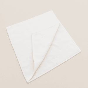 Toalla de microfibra blanca 40x75 cm doblada sobre superficie beige – ideal para uso profesional.