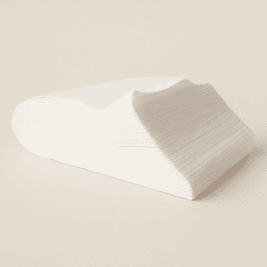 Pack de toallas de celulosa desechables blancas de 40x80 cm apiladas sobre fondo beige.