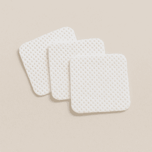 Mini toallitas blancas sin pelusa apiladas, ideales para manicura y tratamientos de uñas.