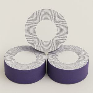 Tres rollos grandes de algodón blanco en presentación profesional de 1 kg, con núcleo interior visible y envoltorio morado.