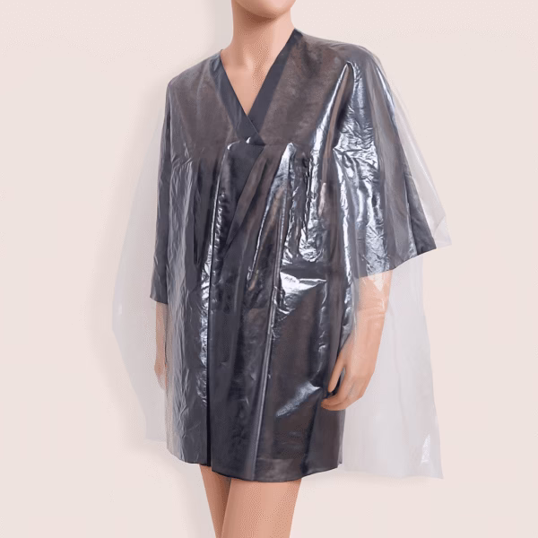 Capa desechable transparente de plástico colocada sobre maniquí negro, ideal para proteger durante tratamientos capilares como tintes o mechas.