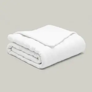 ábana cubrecamillas de algodón rizado ajustable, blanca y doblada sobre un fondo neutro.
